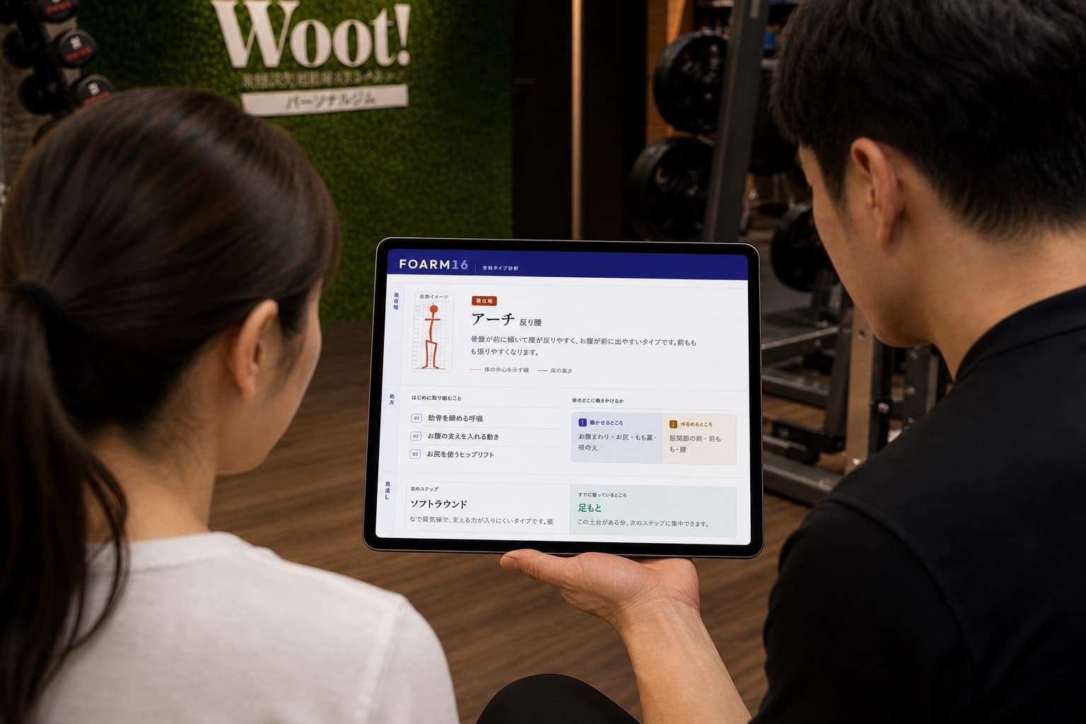 タブレットに表示された FOARM16 の分析画面を見ながら、トレーナーの説明を受ける女性