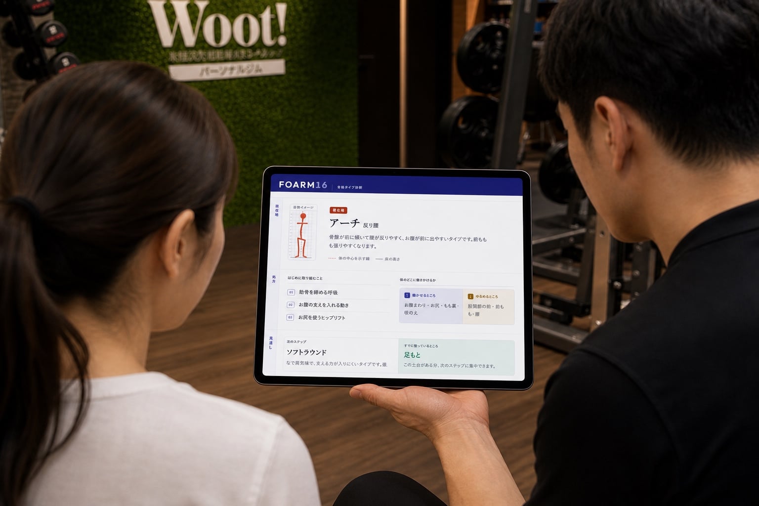 タブレットに表示された FOARM16 の分析画面を見ながら、トレーナーの説明を受ける女性