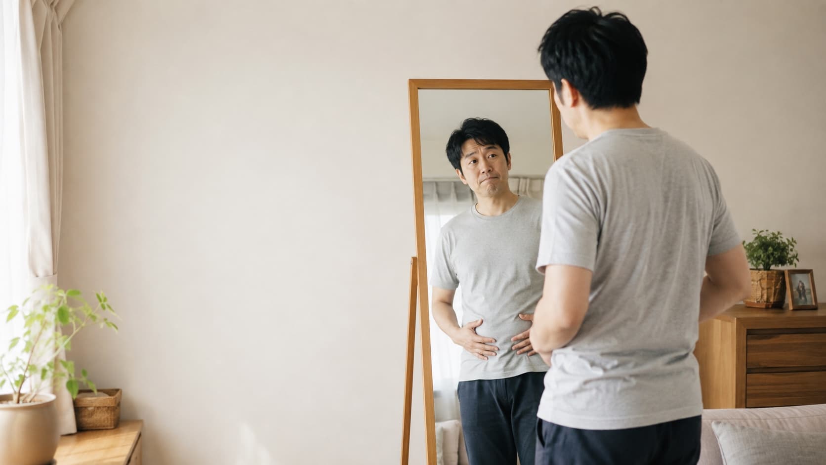 鏡の前で体型を気にする男性