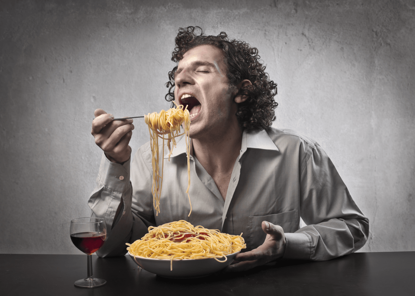 大口を開けてパスタを食べる男性
