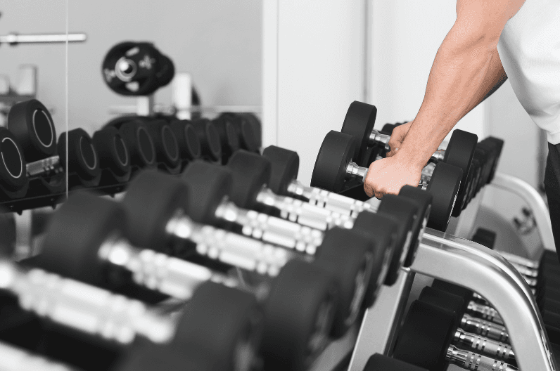 パーソナルジムでダンベルを手に取る男性