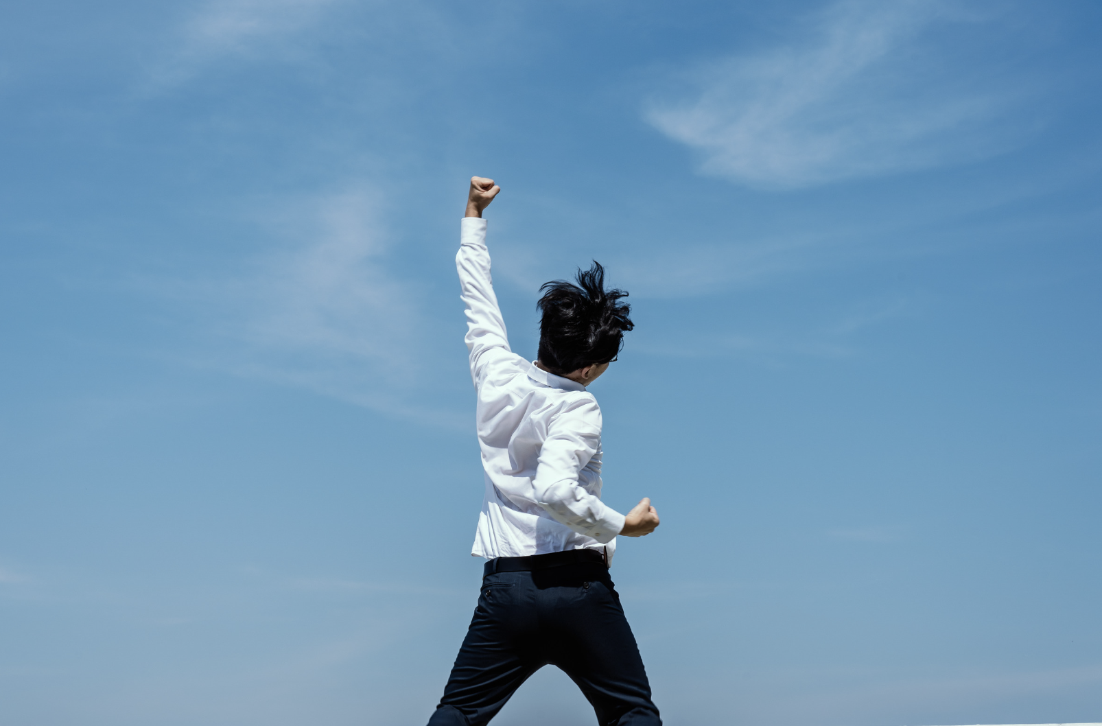 拳を高く突き上げて喜ぶ男性の後ろ姿