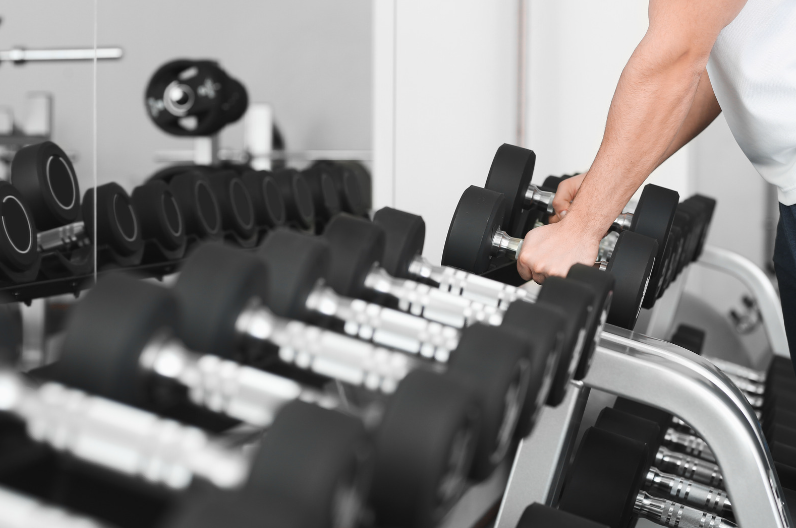 パーソナルジムでダンベルを手に取る男性